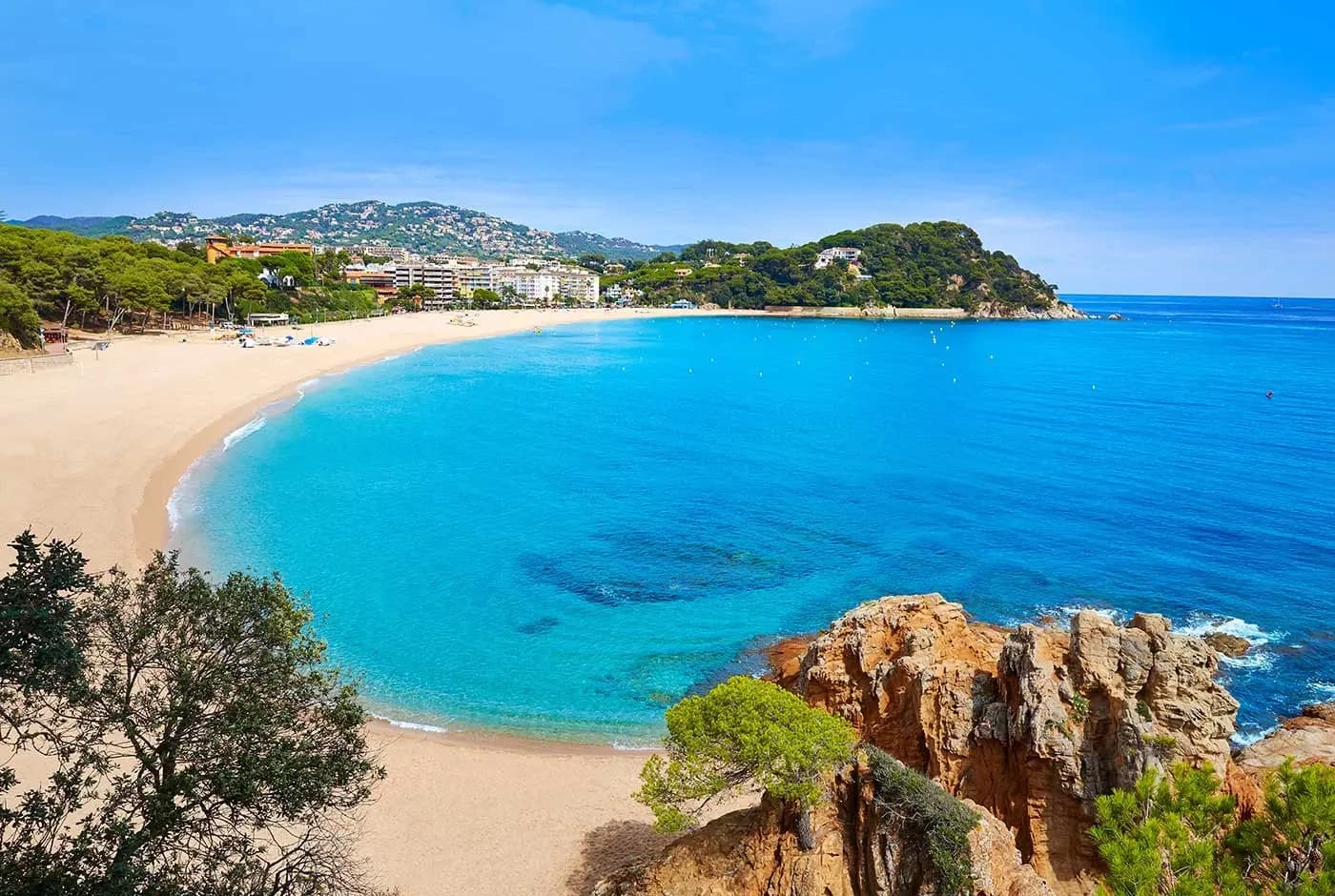 Turquoise water en de gouden zandboog van het strand van Fenals in Lloret de Mar