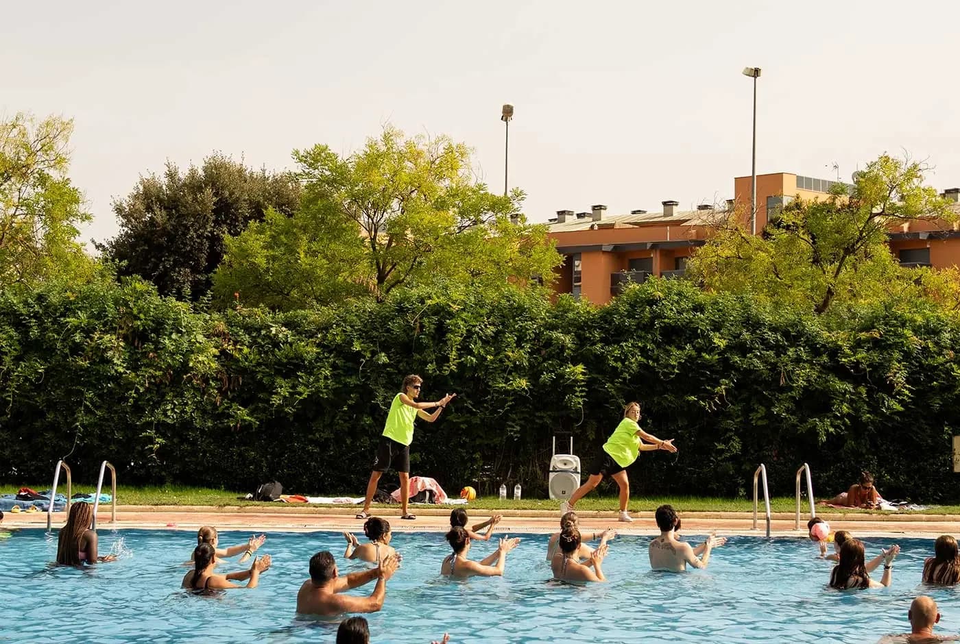 Gasten doen mee aan aquagym in het zwembad, met animatoren aan de rand