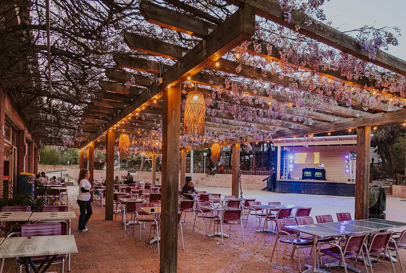 Het terras van het restaurant onder een houten pergola met lichtslingers