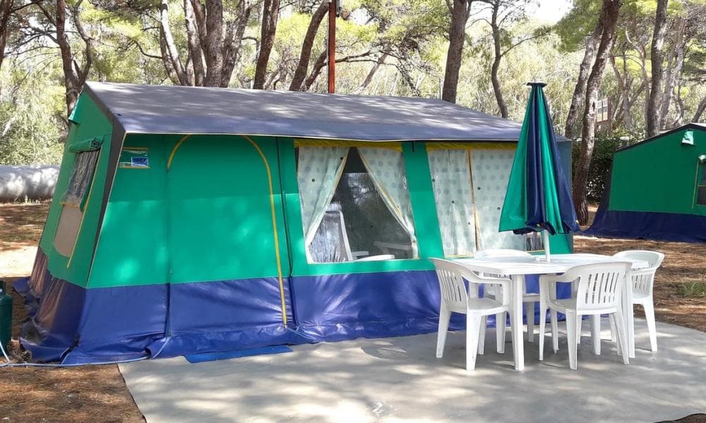 Bungalowtent met terrastafel en parasol onder de pijnbomen